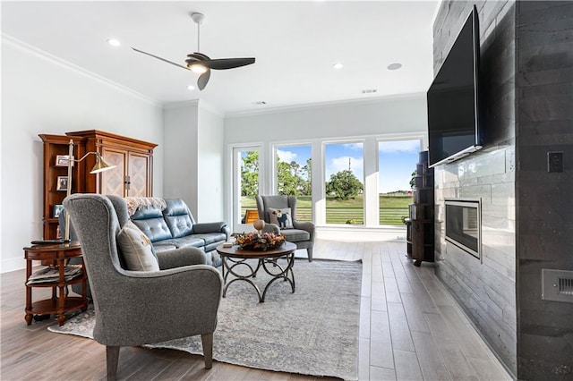 living room with ceiling fan, light wood-type flooring, and crown molding