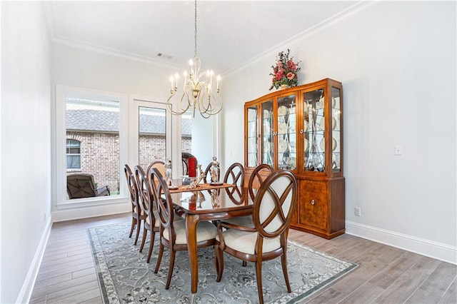 dining area with a notable chandelier, hardwood / wood-style flooring, and ornamental molding