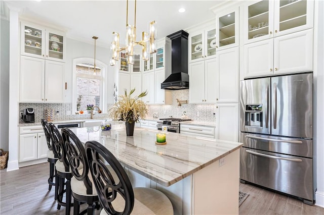 kitchen featuring light hardwood / wood-style floors, stainless steel appliances, a center island, premium range hood, and a notable chandelier