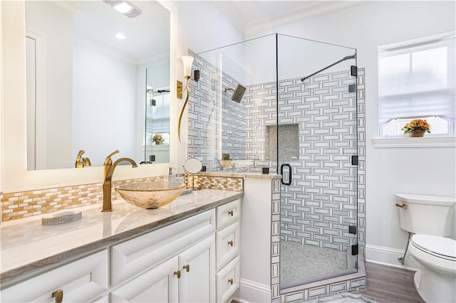 bathroom with hardwood / wood-style flooring, a shower with door, ornamental molding, vanity, and toilet