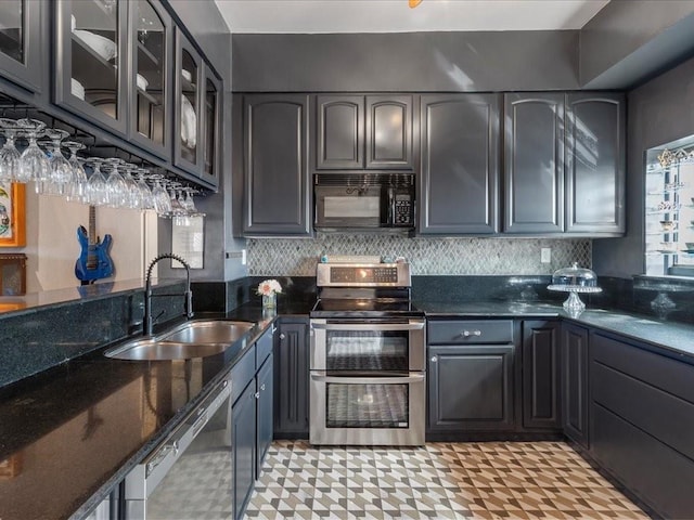 kitchen featuring decorative backsplash, dark stone countertops, appliances with stainless steel finishes, and sink