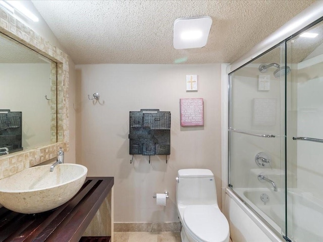 full bathroom with shower / bath combination with glass door, vanity, a textured ceiling, tile patterned floors, and toilet