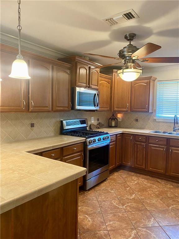 kitchen with backsplash, pendant lighting, stainless steel appliances, ceiling fan, and sink