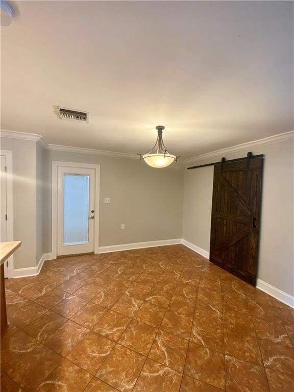 empty room featuring a barn door and ornamental molding