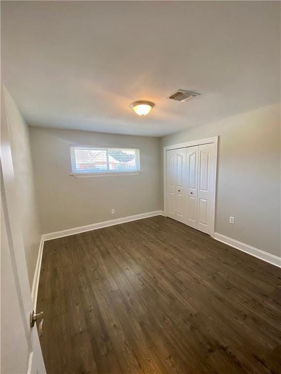 unfurnished bedroom featuring a closet and dark hardwood / wood-style floors