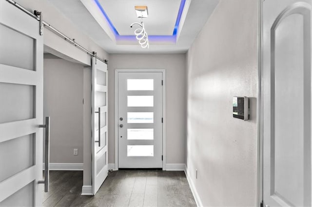 entryway with baseboards, a raised ceiling, a barn door, and wood finished floors