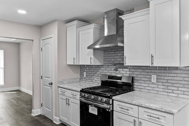 kitchen featuring stainless steel range with gas cooktop, wall chimney range hood, backsplash, and white cabinetry