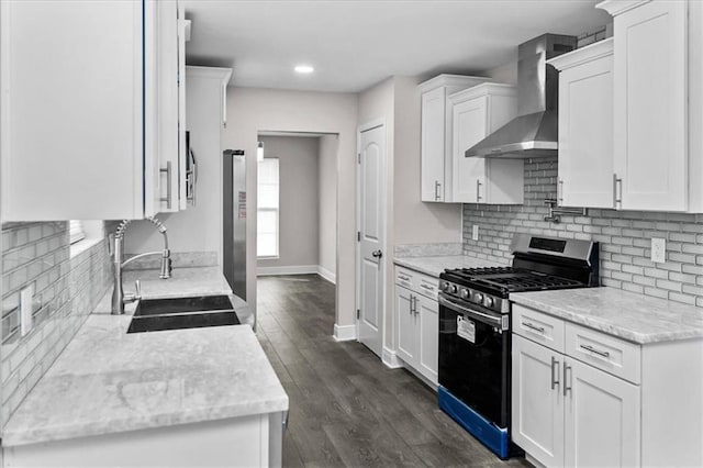 kitchen featuring a sink, white cabinetry, decorative backsplash, wall chimney exhaust hood, and appliances with stainless steel finishes