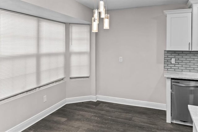 unfurnished dining area featuring dark wood-style flooring and baseboards