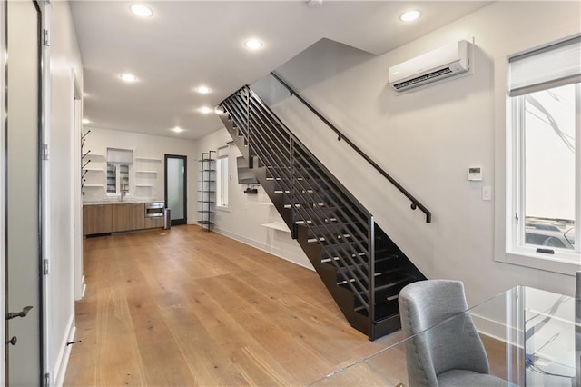 staircase with an AC wall unit and hardwood / wood-style floors