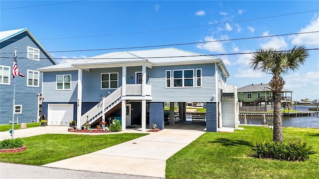 coastal home with a front lawn, a water view, and a carport