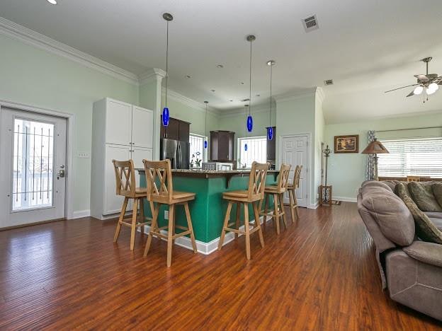 kitchen with ceiling fan, a breakfast bar area, stainless steel fridge, and dark hardwood / wood-style flooring