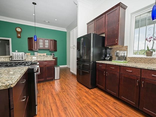 kitchen featuring pendant lighting, high end stainless steel range oven, crown molding, and dark hardwood / wood-style flooring