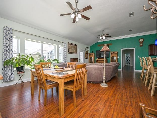 dining space with ornamental molding, vaulted ceiling, ceiling fan, and dark wood-type flooring