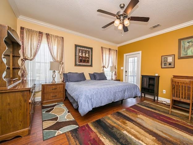 bedroom with ceiling fan, ornamental molding, a textured ceiling, and dark wood-type flooring