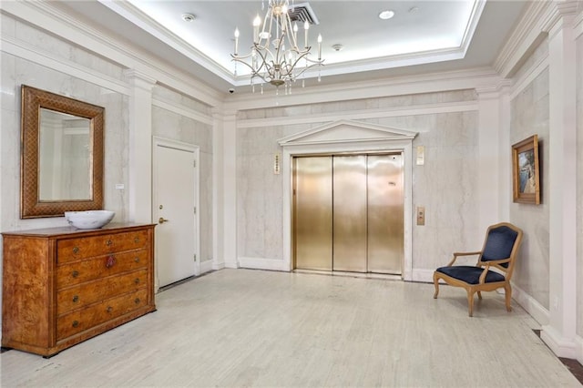 sitting room with elevator, light wood-type flooring, a tray ceiling, an inviting chandelier, and ornamental molding