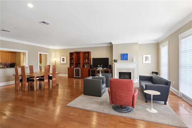 living room featuring beverage cooler, hardwood / wood-style flooring, and crown molding