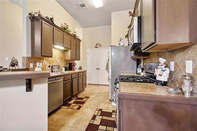 kitchen featuring decorative backsplash, tile counters, appliances with stainless steel finishes, and sink