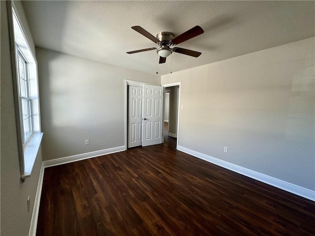 unfurnished bedroom with ceiling fan, a textured ceiling, and dark wood-type flooring