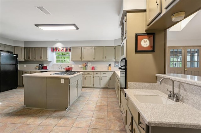 kitchen featuring stainless steel appliances, light tile patterned floors, a kitchen island, and sink