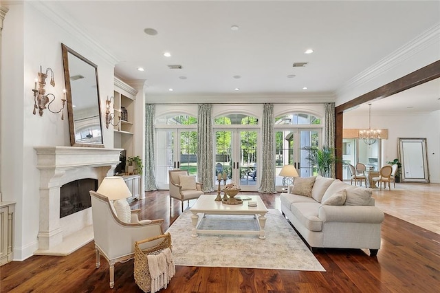 living room with french doors, a premium fireplace, dark wood-type flooring, an inviting chandelier, and crown molding