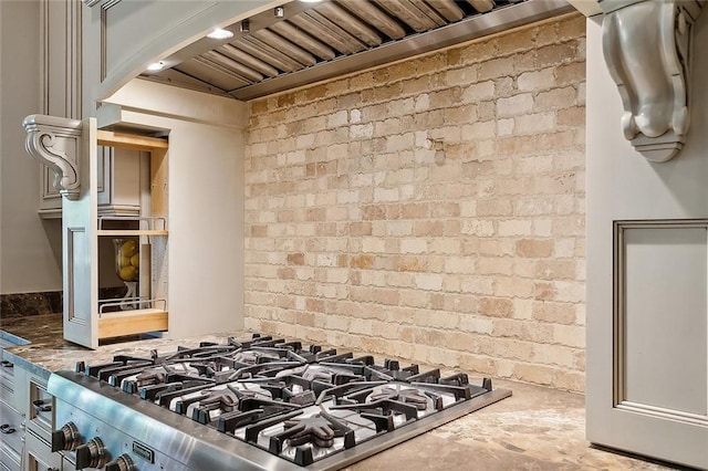 kitchen featuring brick wall, custom range hood, concrete floors, and stainless steel range oven