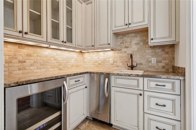 kitchen with backsplash, beverage cooler, light stone counters, and sink