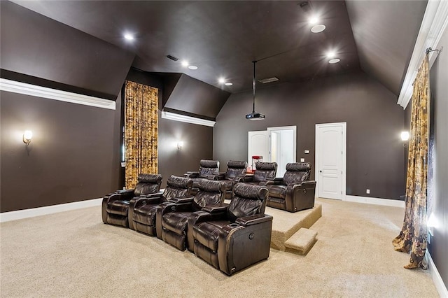 carpeted home theater room with ornamental molding and vaulted ceiling