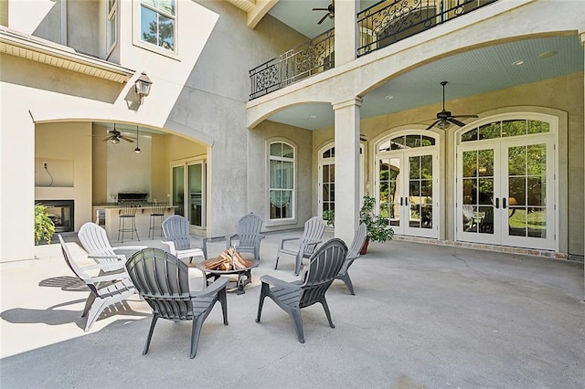 view of patio / terrace featuring a balcony, ceiling fan, french doors, and a fire pit