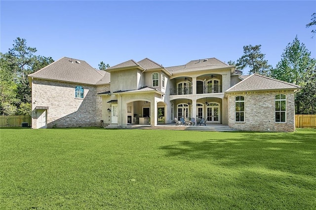 back of property featuring a balcony, a patio, and a yard