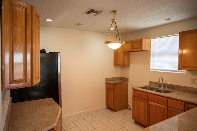 kitchen with a textured ceiling, light tile patterned floors, decorative light fixtures, and sink