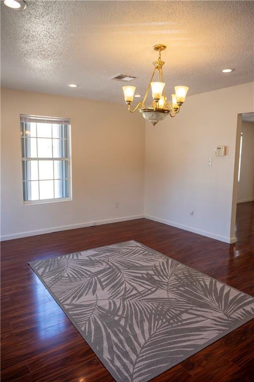 interior space with a textured ceiling, dark wood-type flooring, and a notable chandelier