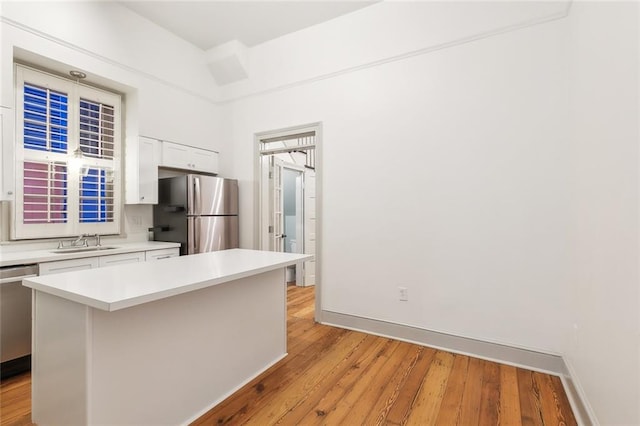 kitchen featuring sink, white cabinetry, appliances with stainless steel finishes, a center island, and light hardwood / wood-style floors