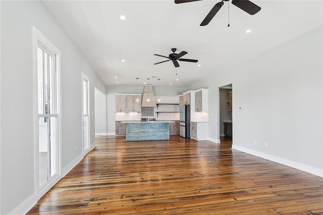 unfurnished living room featuring ceiling fan and dark hardwood / wood-style floors