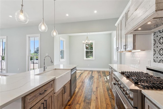 kitchen with hardwood / wood-style floors, hanging light fixtures, sink, custom range hood, and appliances with stainless steel finishes