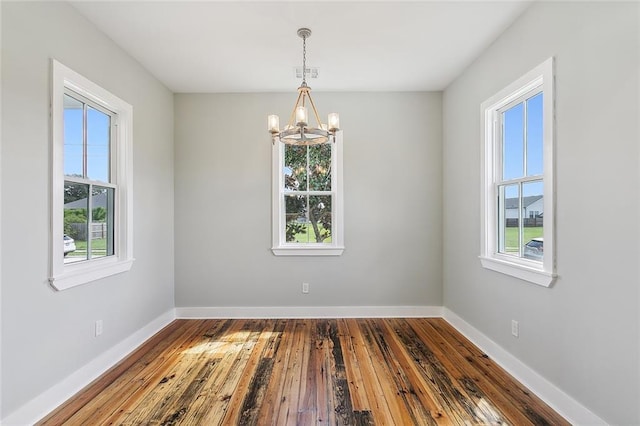 spare room featuring a chandelier and wood-type flooring