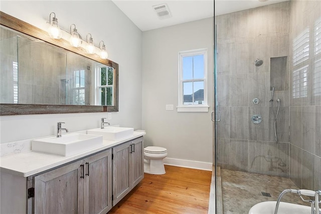 bathroom featuring vanity, wood-type flooring, a healthy amount of sunlight, and toilet