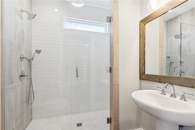 bathroom featuring a shower with shower door and sink