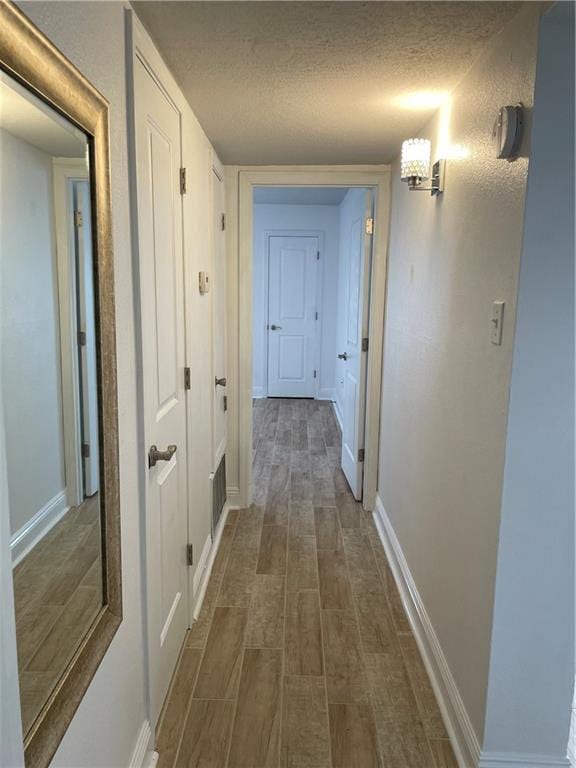 hall with a textured ceiling and dark wood-type flooring