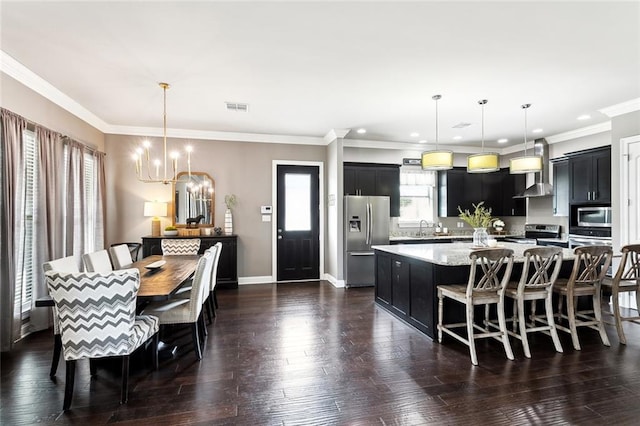 kitchen featuring appliances with stainless steel finishes, dark wood-type flooring, a kitchen island, pendant lighting, and an inviting chandelier