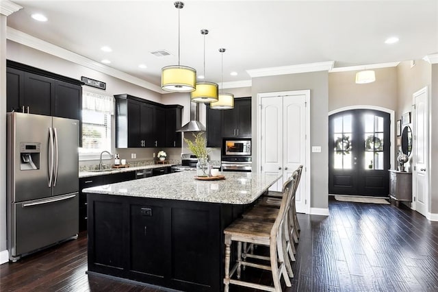 kitchen with hanging light fixtures, a kitchen island, dark wood-type flooring, appliances with stainless steel finishes, and crown molding