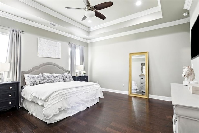 bedroom with ceiling fan, a raised ceiling, dark hardwood / wood-style floors, and crown molding