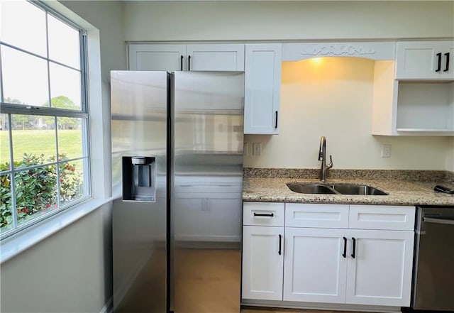 kitchen featuring white cabinetry, sink, stainless steel appliances, and light stone counters