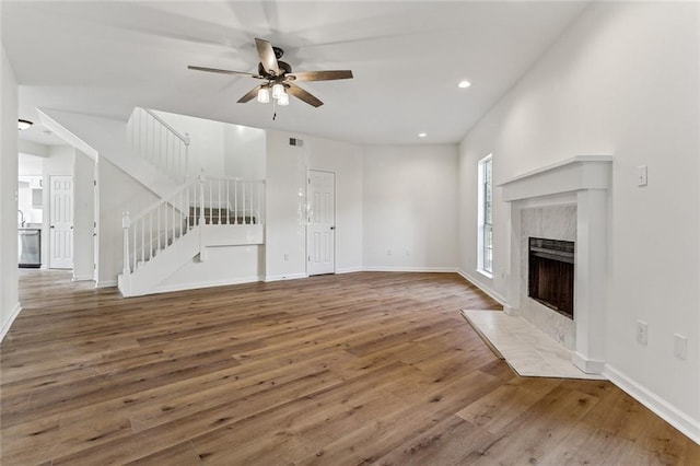 unfurnished living room featuring a high end fireplace, hardwood / wood-style floors, and ceiling fan