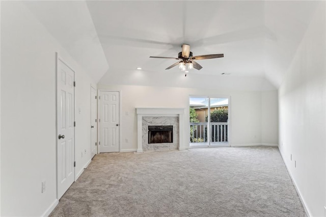 unfurnished living room with ceiling fan, a premium fireplace, vaulted ceiling, and light carpet