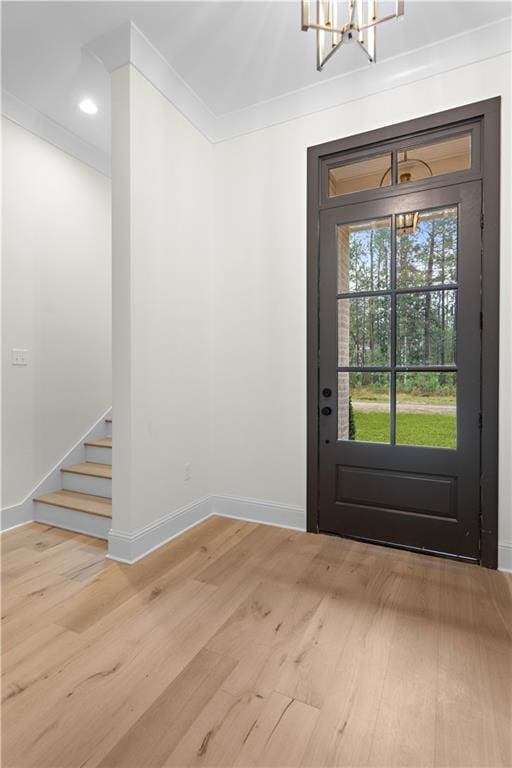 entrance foyer featuring hardwood / wood-style flooring, an inviting chandelier, and crown molding