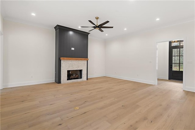 unfurnished living room with ceiling fan, light wood-type flooring, crown molding, and a fireplace