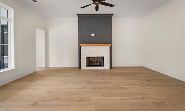 unfurnished living room with ceiling fan, light wood-type flooring, ornamental molding, and a fireplace