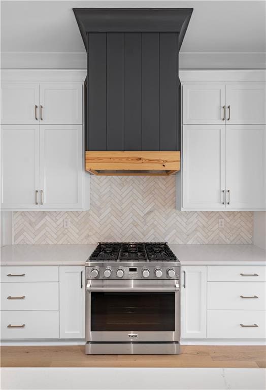 kitchen with white cabinets, backsplash, and stainless steel stove