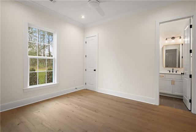 unfurnished bedroom featuring sink, ensuite bathroom, ceiling fan, light hardwood / wood-style floors, and crown molding